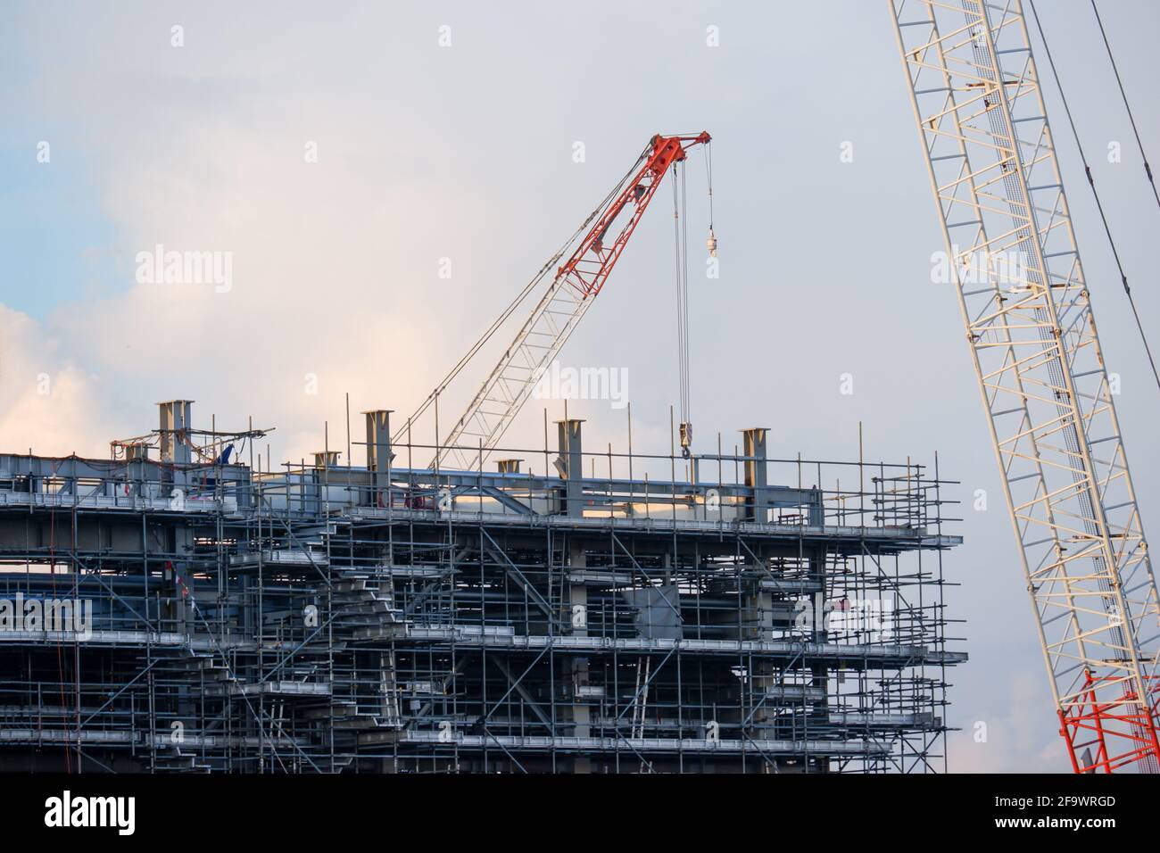 Bau Turmkran der Kran ist von Gerüsten mit schönen Wolken im Hintergrund umgeben. Stockfoto