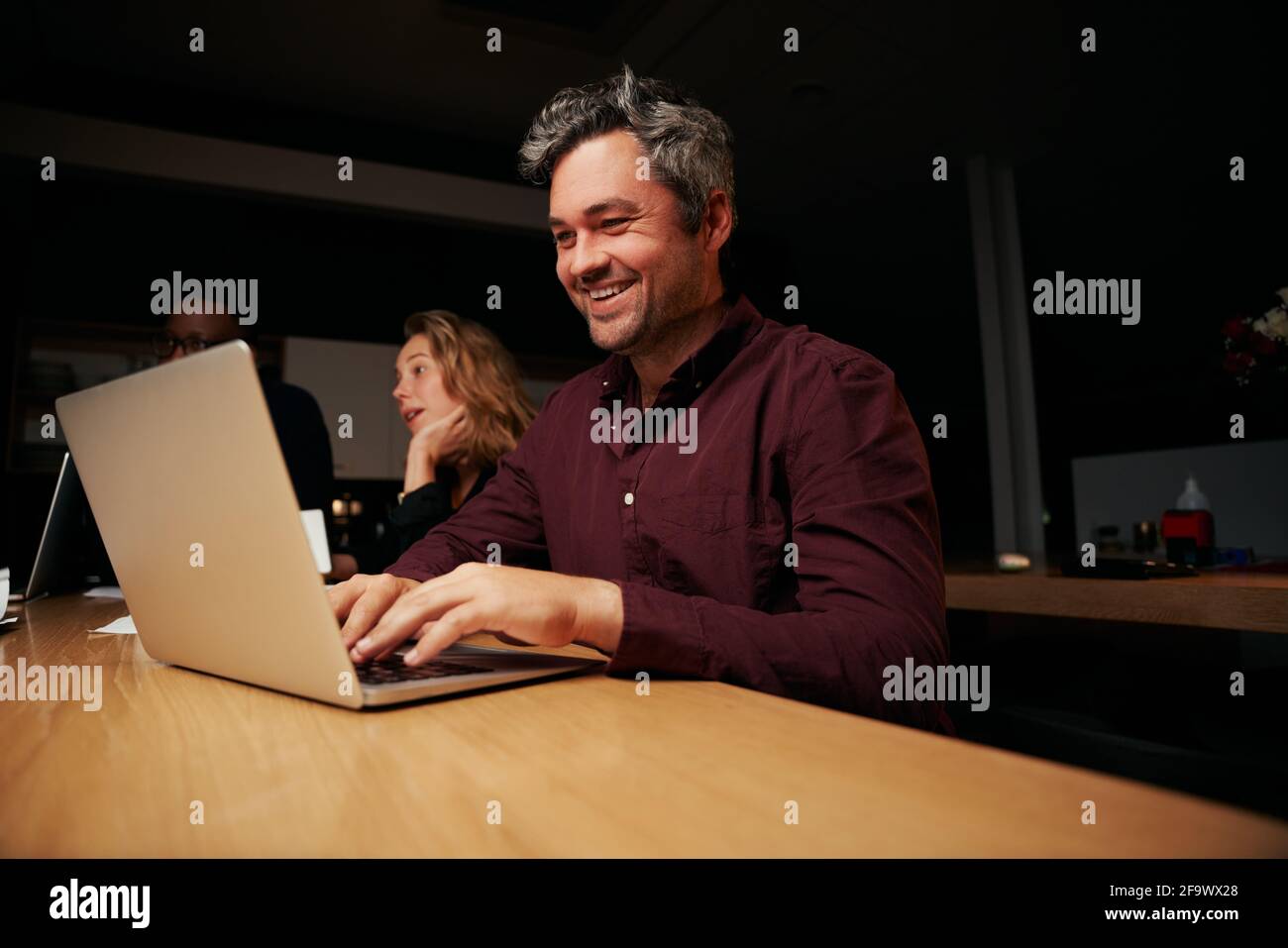 Porträt eines erfolgreichen Geschäftsmannes mittleren Alters, der auf dem Laptop tippt Am Arbeitsplatz Stockfoto