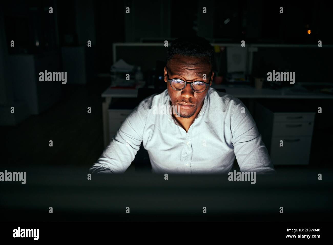 Fokussierter junger afrikanischer Geschäftsmann, der spät an seinem Schreibtisch arbeitet In der Nacht Stockfoto