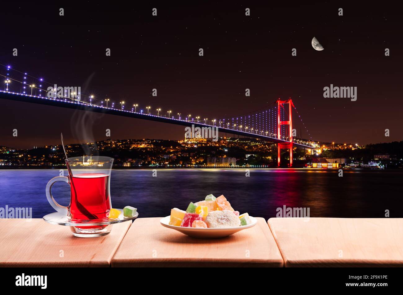 Beleuchtete Bosporus-Brücke bei Nacht und traditioneller türkischer Tee, Istanbul Stockfoto