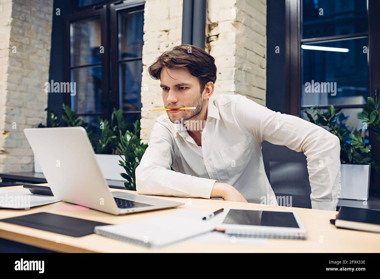 Fokussierter Geschäftsmann, der im Büro an einem Laptop arbeitet Stockfoto