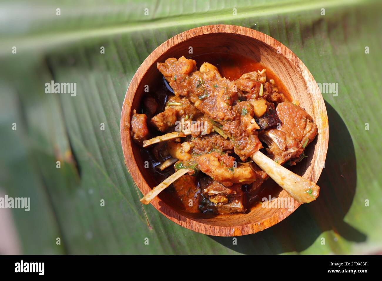 Hammelfleisch zerkleinert das urige. Indisches rustikales würziges, nicht-vegetarisches Ziegenfleisch-Indische, in einer Holzschüssel über einem Bananenblatt-Hintergrund servierte, Platz zum Kopieren. Stockfoto