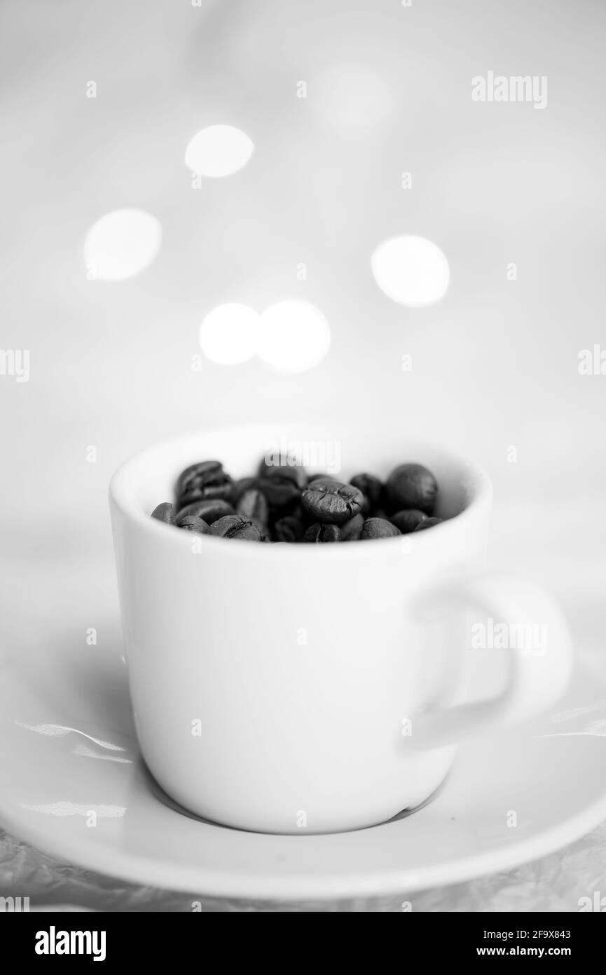 Kaffeetasse gefüllt mit Kaffeebohnen, vertikales Schwarz-Weiß-Foto Stockfoto