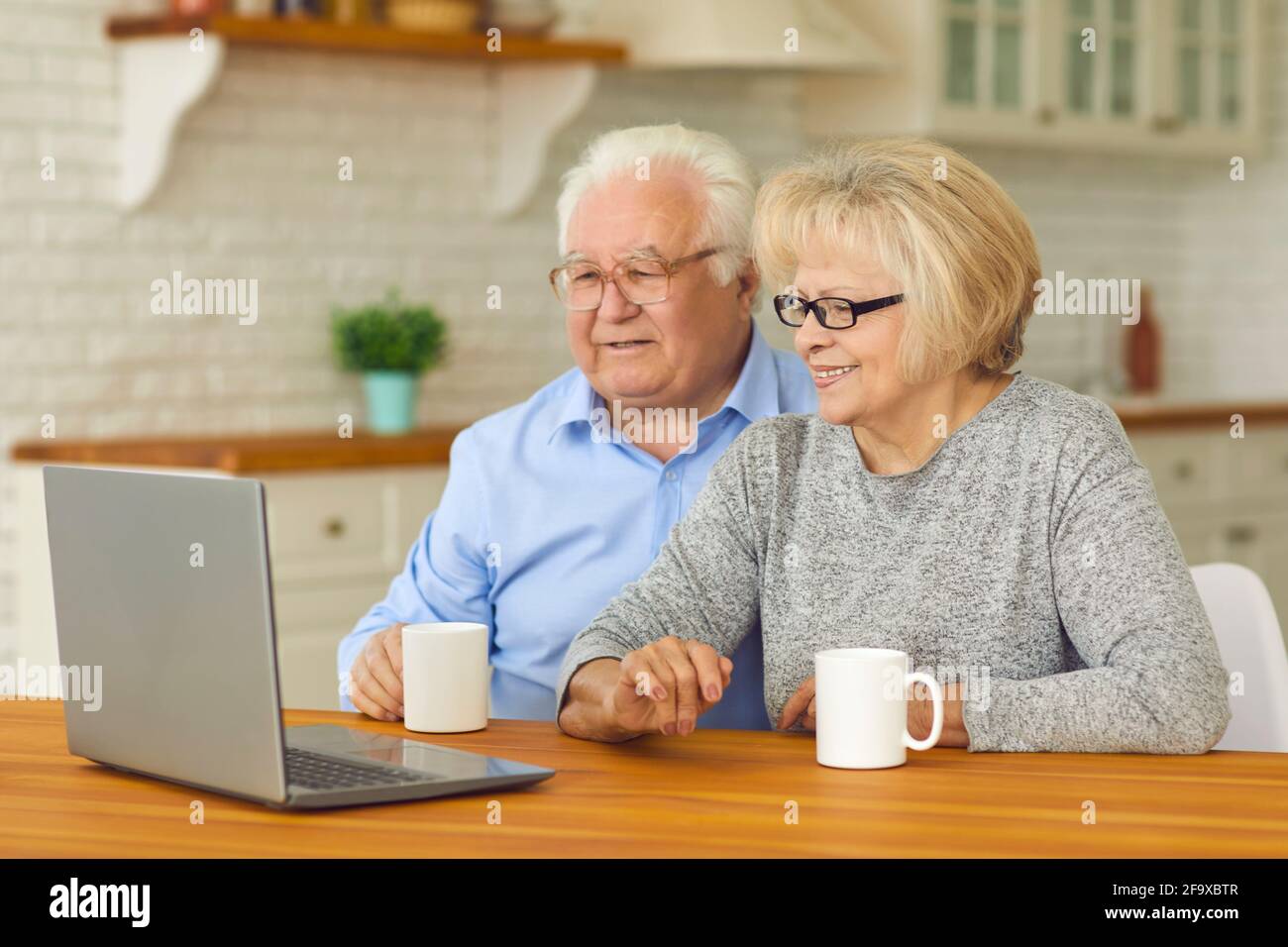 Glückliches reifes Paar, das vor dem Laptop-Computer sitzt Heim- und Videoanrufe bei Enkelkindern Stockfoto