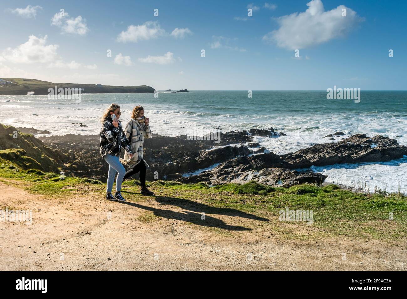 Zwei Freundinnen, die auf dem Küstenpfad auf der Landzunge in Newquay in Cornwall spazieren. Stockfoto