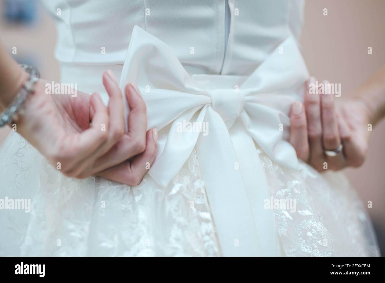 Nahaufnahme der Braut, die ihren Bogen auf sie fixiert Weißes Hochzeitskleid Stockfoto