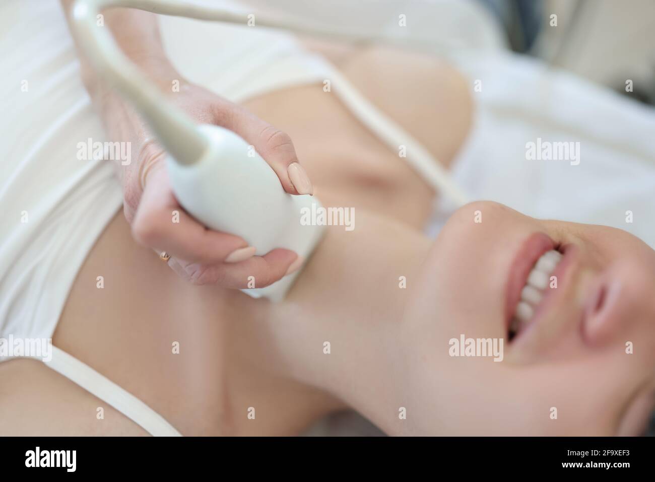Der Arzt führt Ultraschalluntersuchung der Schilddrüse der Frau durch Stockfoto