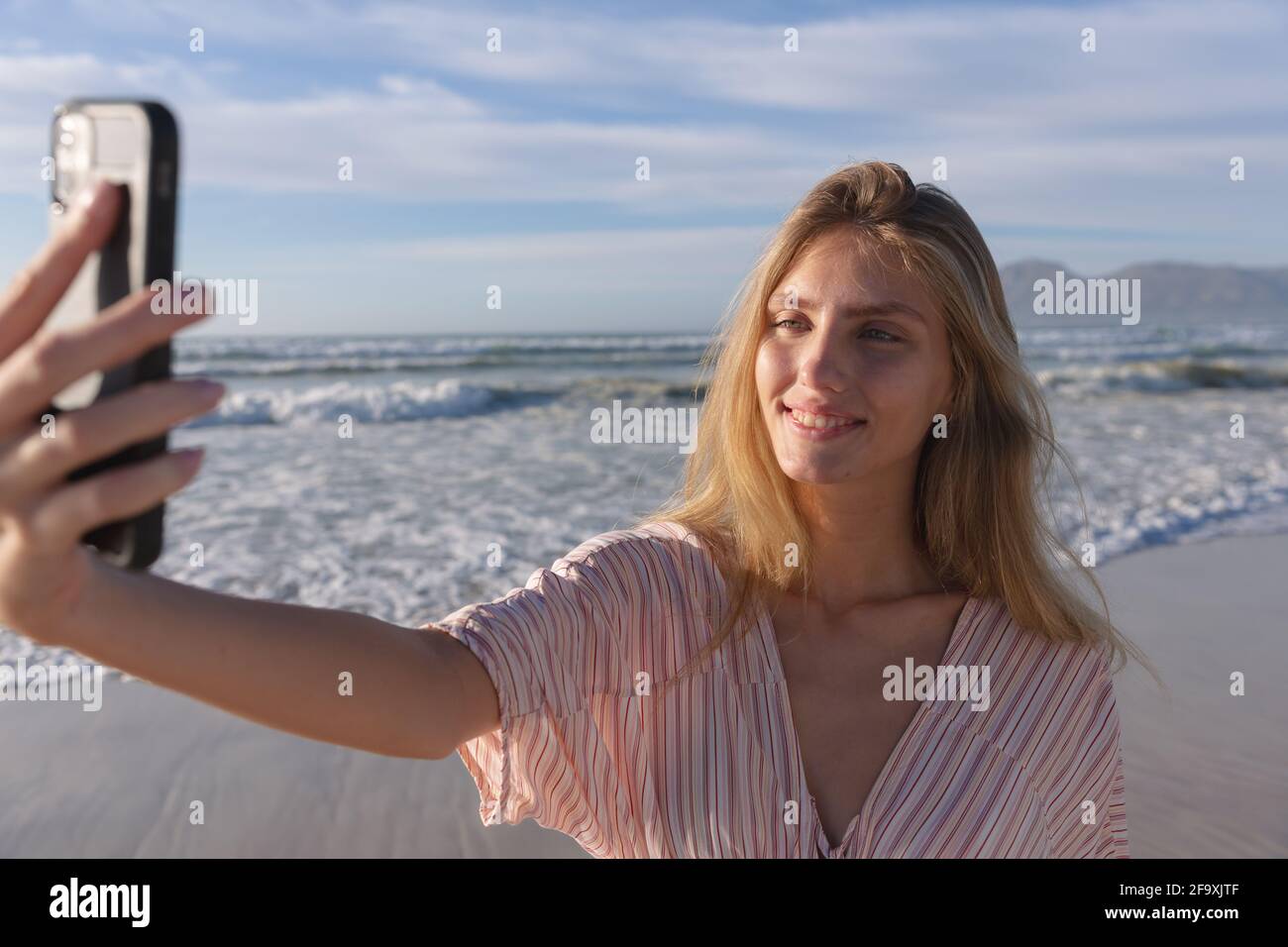 Kaukasische Frau trägt Strandvertuschung nimmt ein Selfie mit Smartphone am Strand Stockfoto