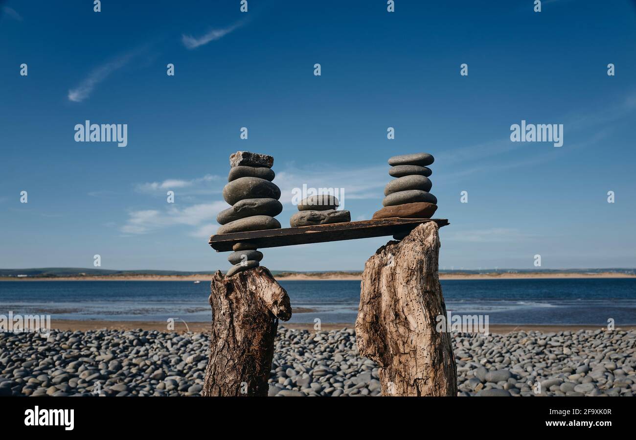 Eine Strandskulptur eines Turms aus Kieselsteinen, gestapelt auf Treibholz in Westward Ho! Beach, Devon, Großbritannien Stockfoto