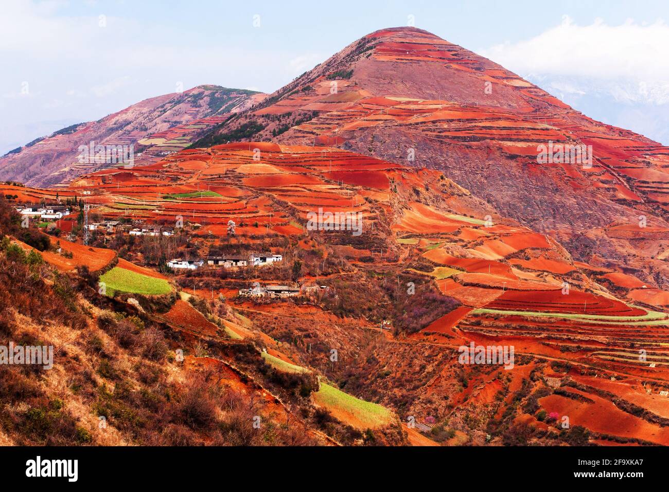 Atemberaubende Landschaft mit Weizenterrassen und alten Dorf auf den hohen Bergen, fantastische Aussicht auf das „Rote Land“ von Dongchuan, China. Stockfoto