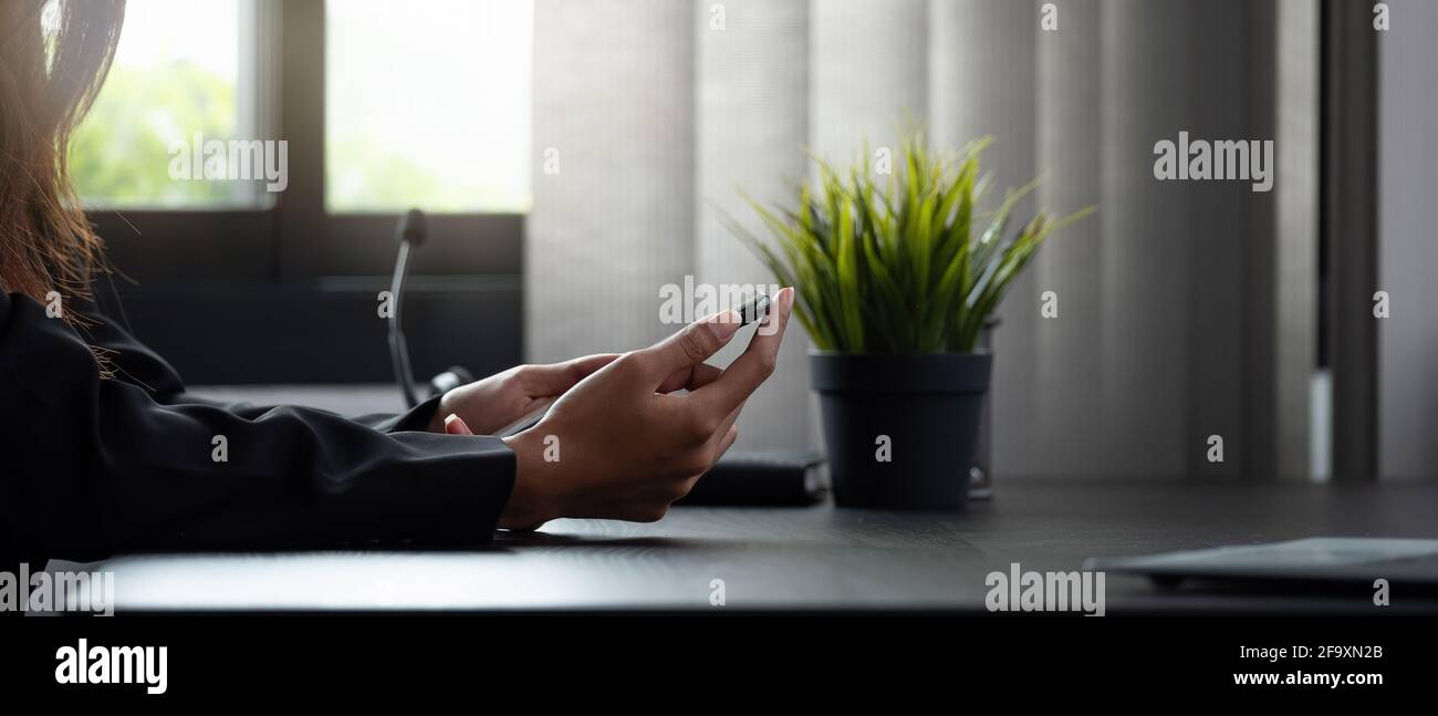 Nahaufnahme der Frau, die ihr Smartphone in ihrem Büro nutzt Stockfoto