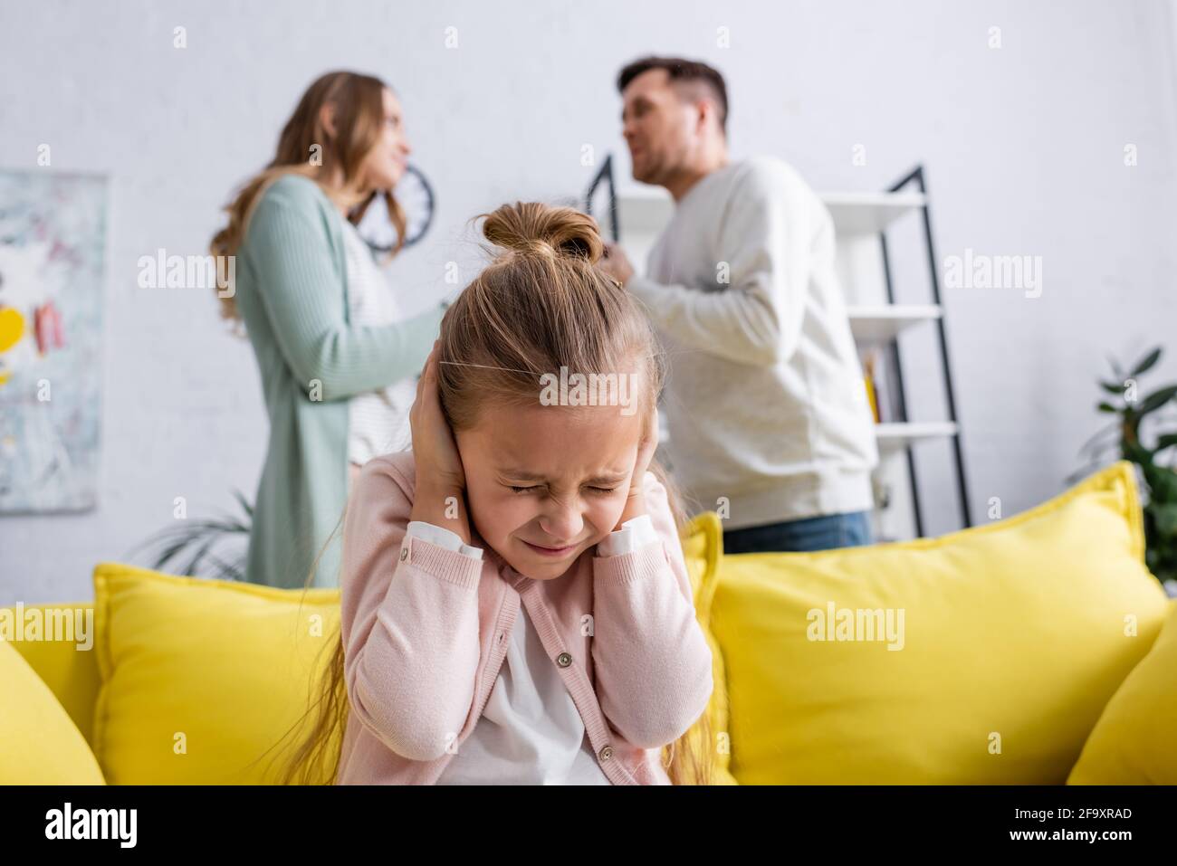 Mädchen bedeckt Ohren in der Nähe von Eltern streiten zu Hause Stockfoto