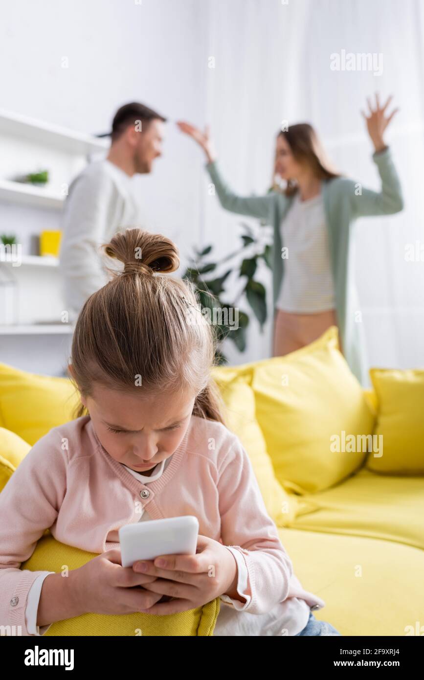 Kind mit Smartphone, während Eltern zu Hause streiten Stockfoto