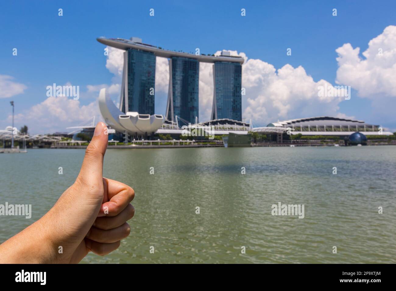 Daumen hoch vor Marina Bay Sands, Singapur. Ein Reisemoment am weltberühmten Wahrzeichen der Stadt. Beliebter Urlaub und sicheres Stadtziel. Stockfoto