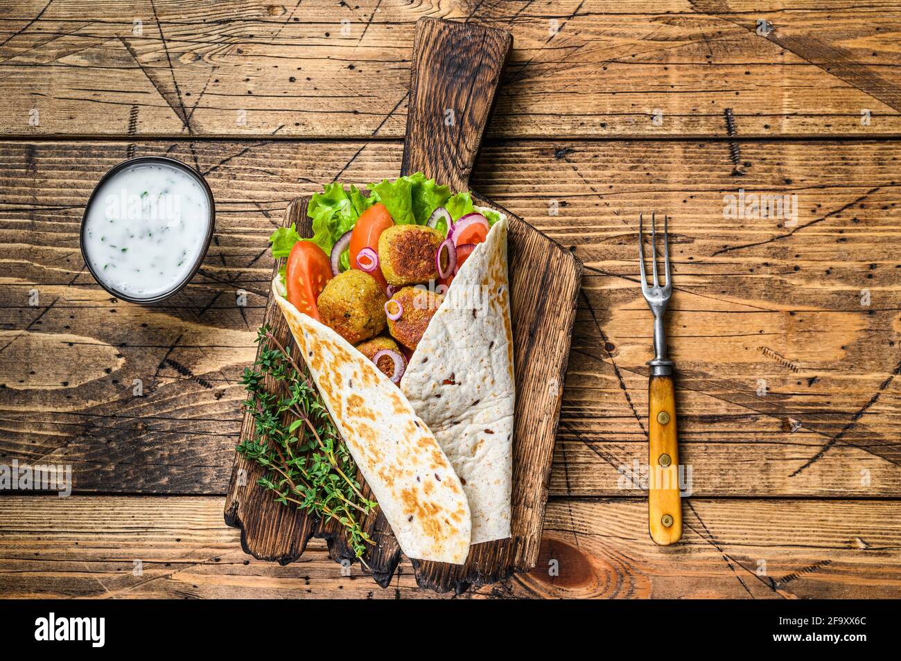 Vegetarische Tortilla Wrap mit Falafel und frischem Salat, vegane Tacos. Holzhintergrund. Draufsicht Stockfoto