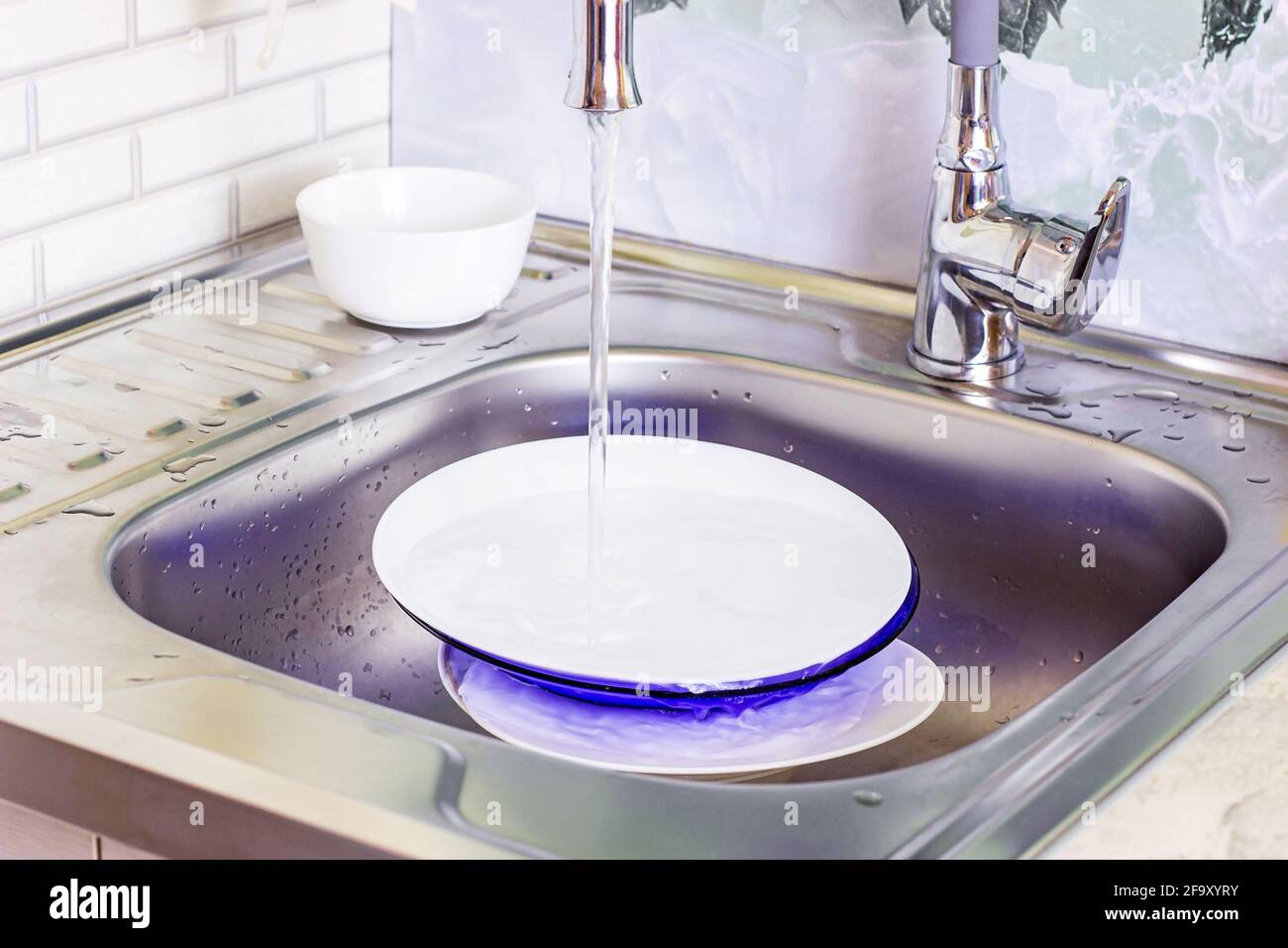 Metallwaschbecken in der Küche voller schmutziger Geschirrstapel. Hausarbeit, Geschirr waschen, Haushaltsaufgaben Konzept. Stockfoto