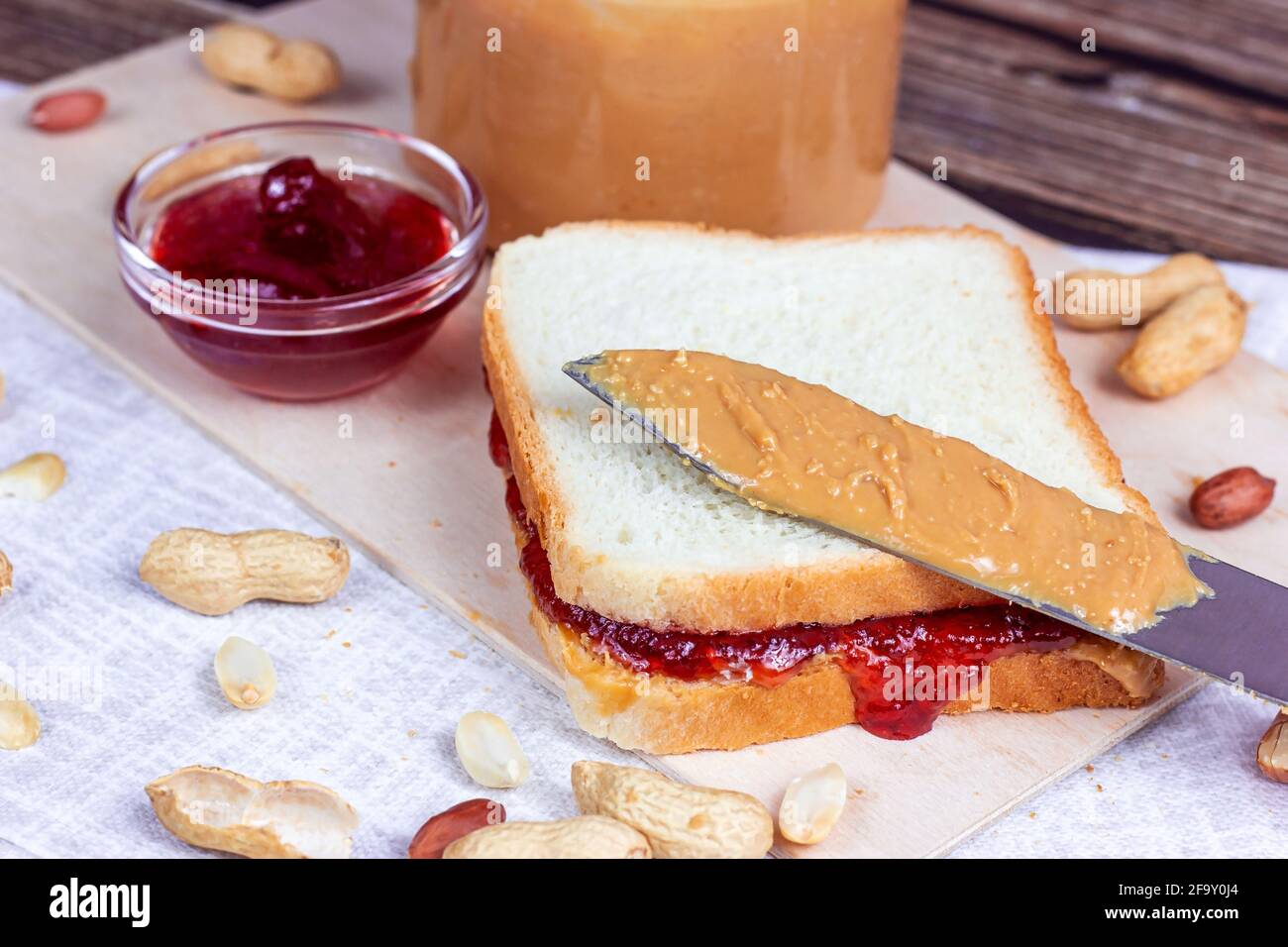 Hausgemachtes Sandwich zum Frühstück mit frischer knackiger Erdnussbutter und Erdbeergelee auf hellem Hintergrund. Stockfoto