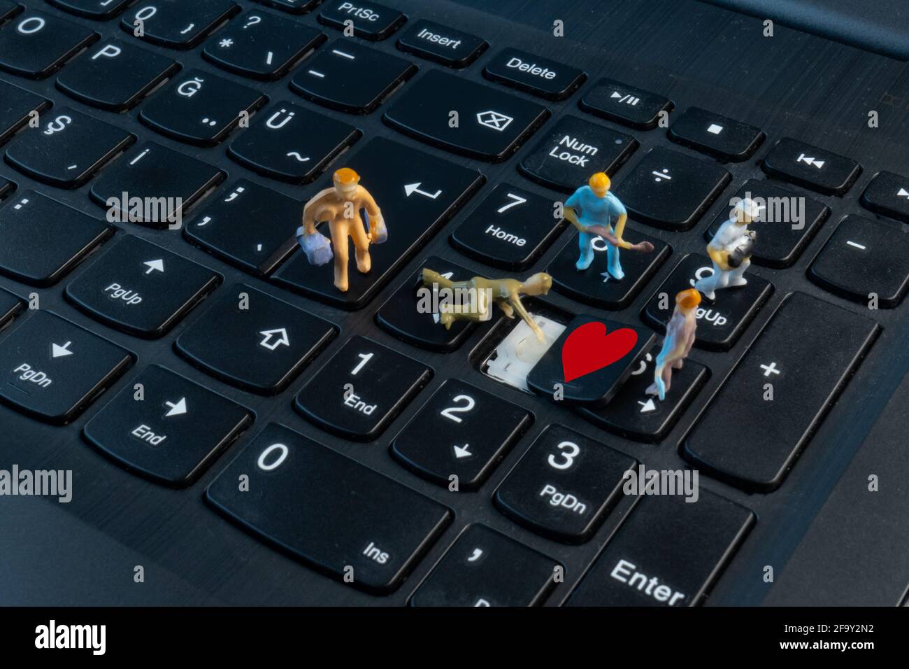 Mini-Mitarbeiter arbeiten auf der Tastatur an Liebe Stockfoto