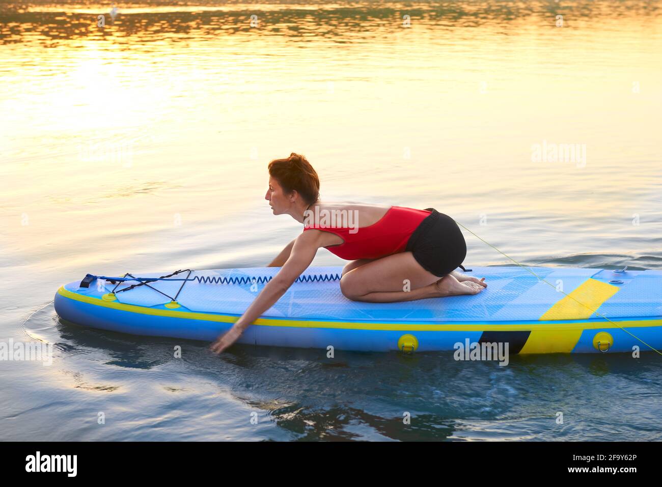 Eine Frau, die am schönen Morgen auf einem Fluss paddelt Stockfoto