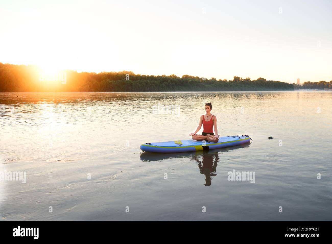 Meditieren auf einem Paddleboard während eines wunderschönen Morgensonnenaufgangs Stockfoto