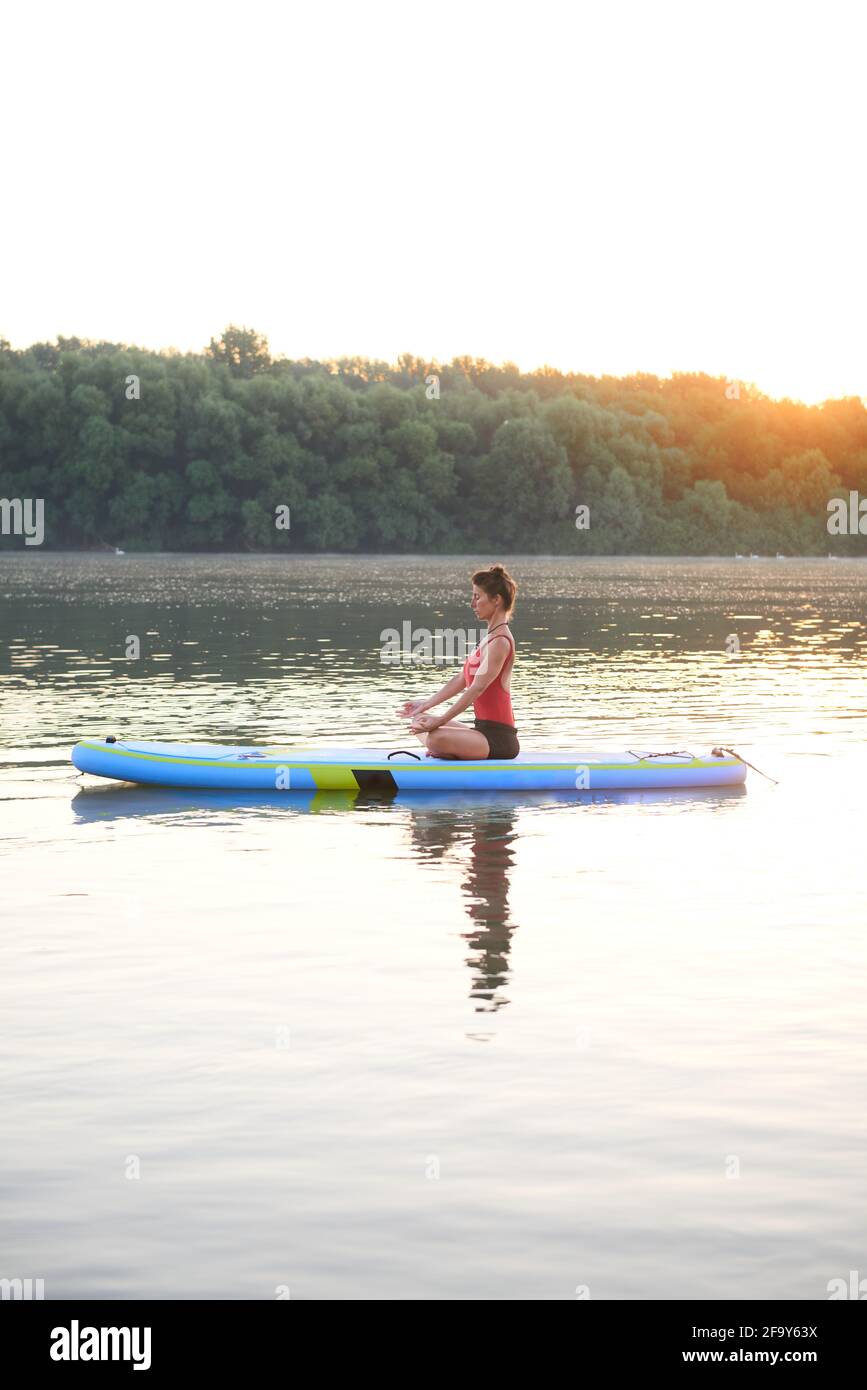 Yoga an einem schönen Morgen auf einem Paddleboard üben Stockfoto