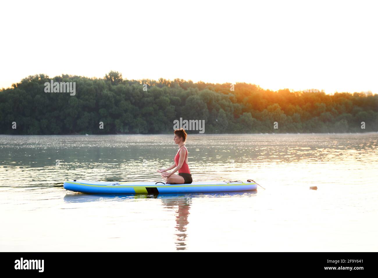 Yoga an einem schönen Morgen auf einem Paddleboard üben Stockfoto