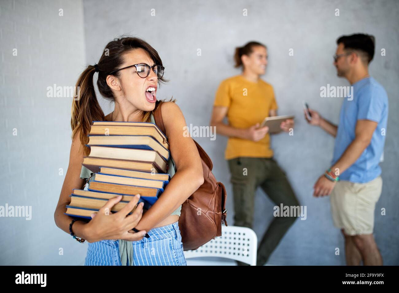 Unglücklich Student Mädchen Blick auf ihre faulen Kumpels, die sind Spielen mit dem Telefon statt zu arbeiten Stockfoto