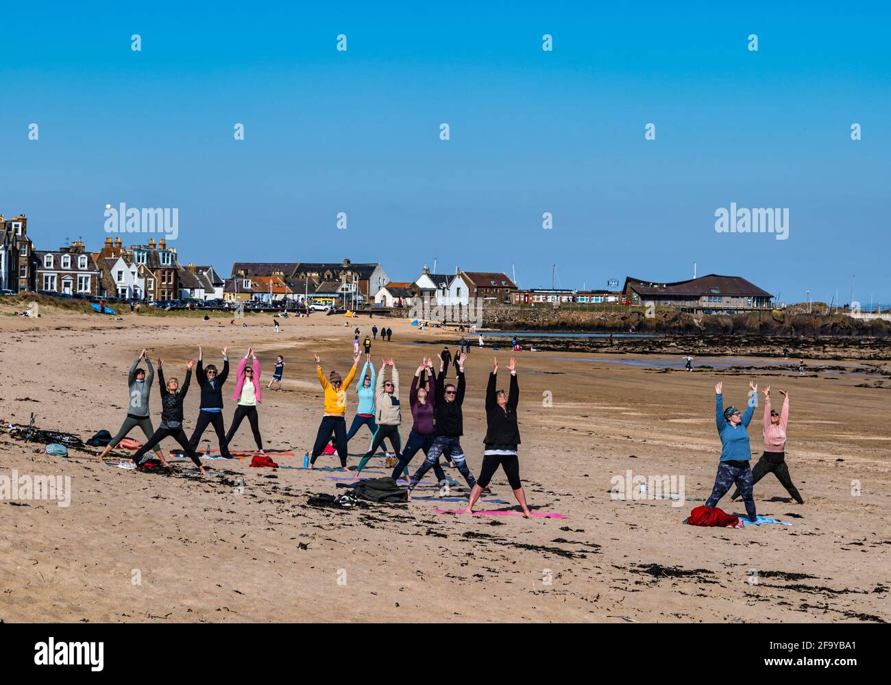 Menschen, die den Strand bei Sonnenschein mit Frauen im Yoga-Kurs genießen, North Berwick, East Lothian, Schottland, Großbritannien Stockfoto