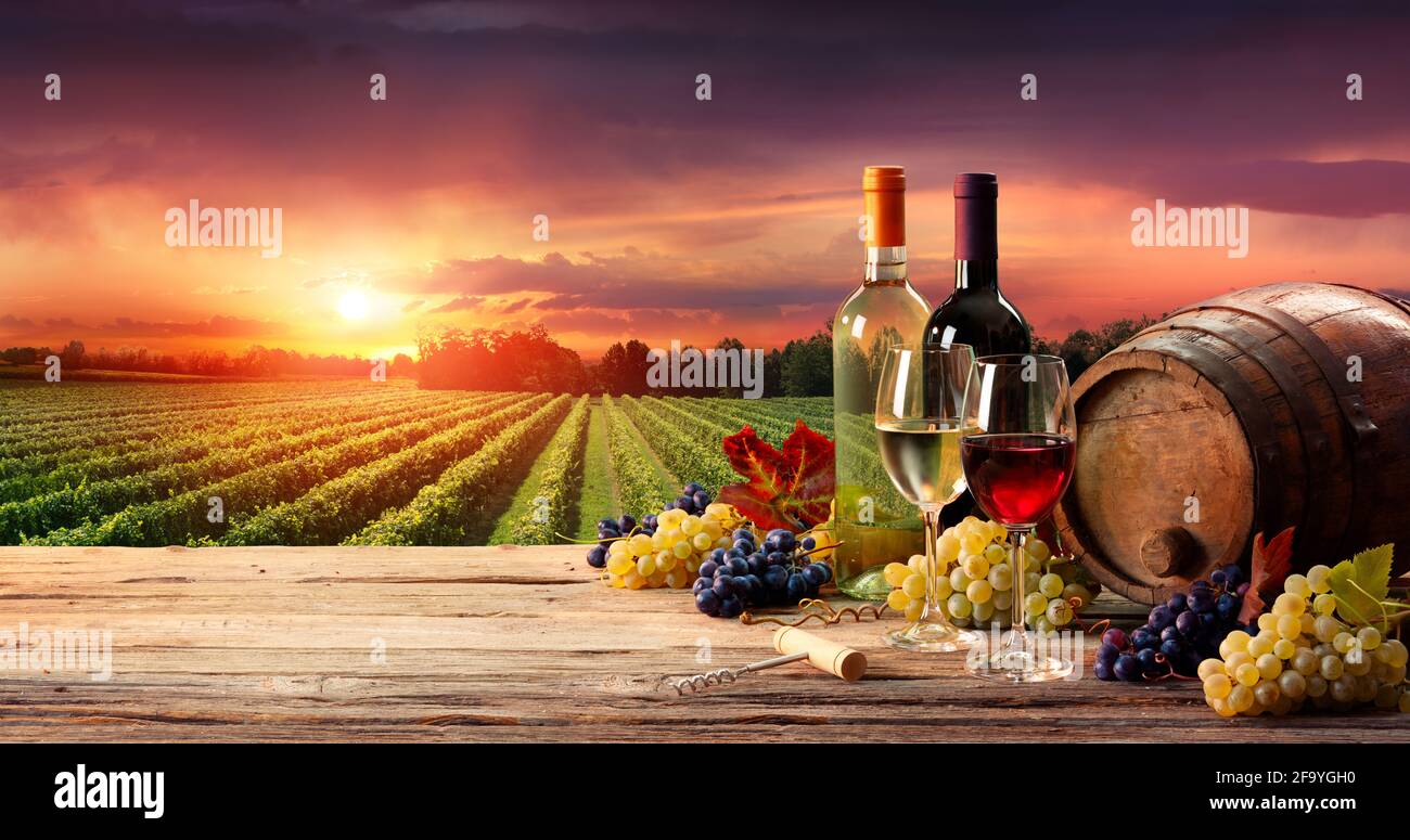 Barrel Weingläser Und Flasche In Vineyard Bei Sonnenuntergang Stockfoto