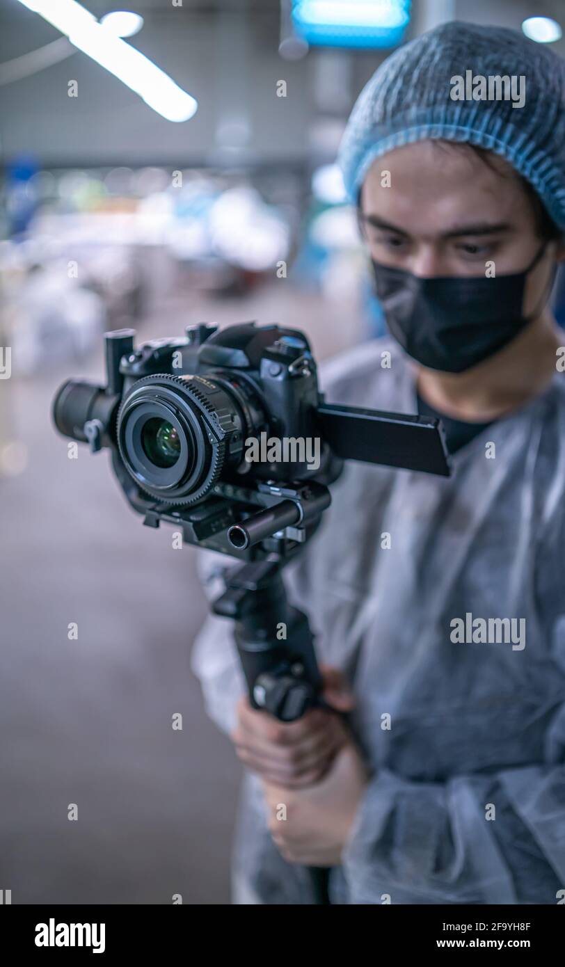 Junger Bediener im medizinischen Schutzanzug mit Kamera Stockfoto
