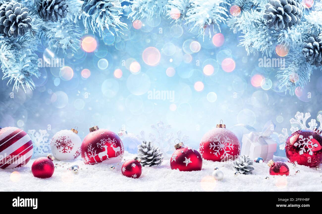 Weihnachten - Rote Ornamente Auf Schnee Mit Tannenzweigen Stockfoto