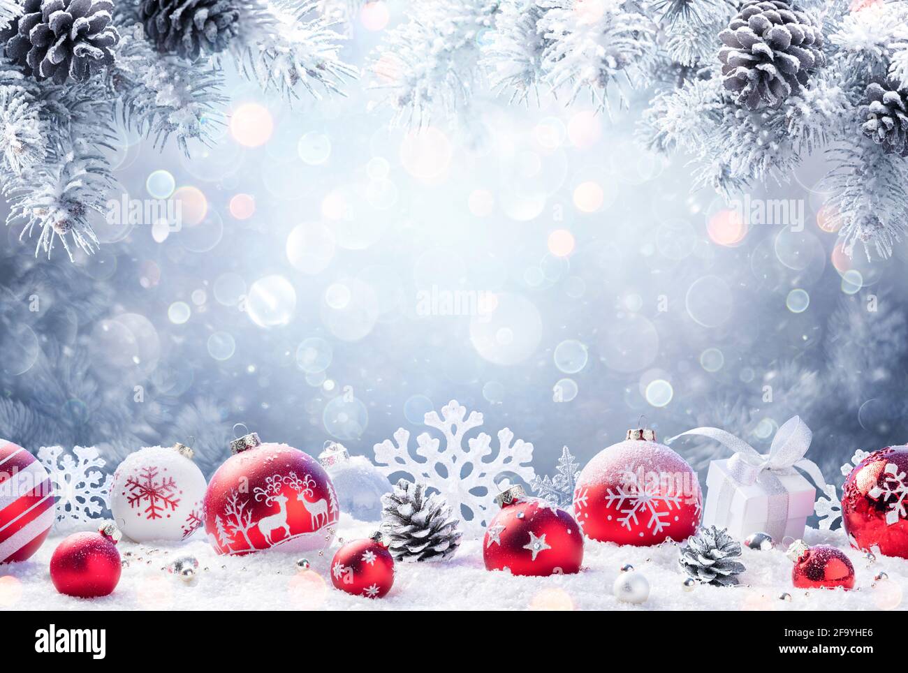 Weihnachten - Rote Ornamente Auf Schnee Mit Tannenzweigen Stockfoto