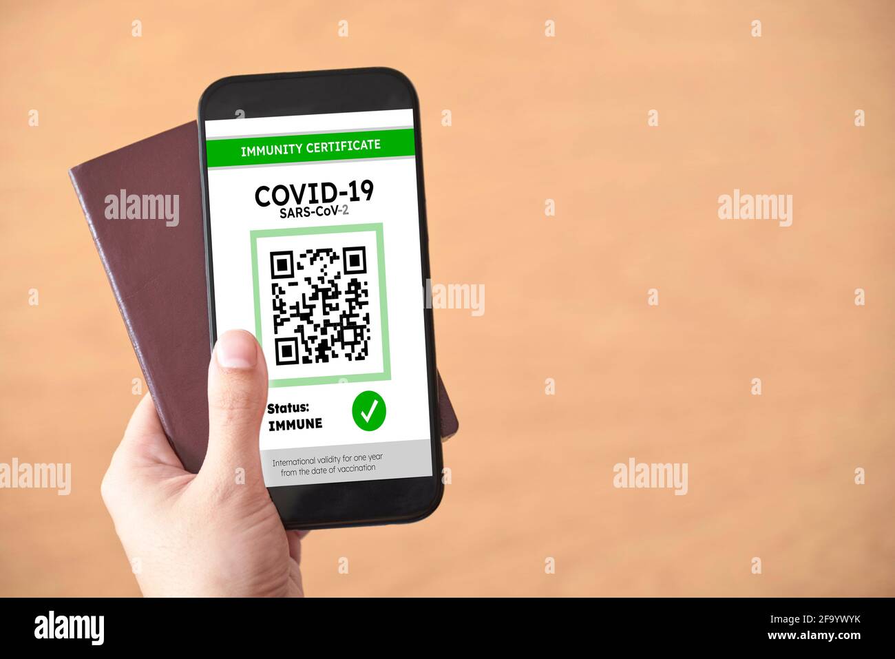 Hand mit einem Reisepass und einem Smartphone mit einem Covid19-Immunitätszertifikat auf dem Bildschirm. Reisekonzept während der Corona-Virus-Pandemie. Bild Stockfoto
