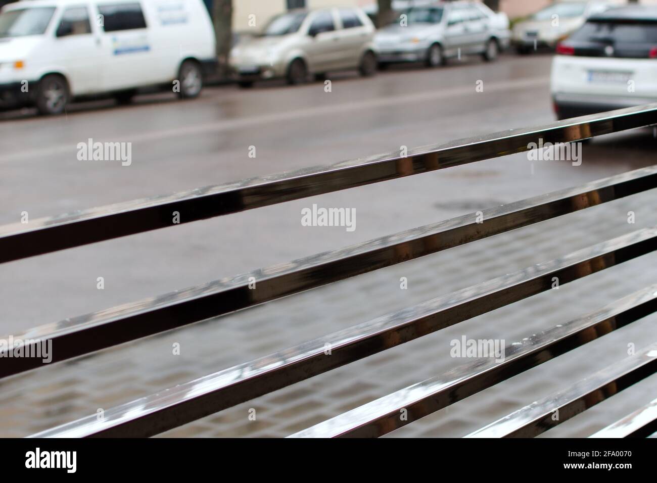 Verschwommener Hintergrund des Stadtverkehrs an regnerischen Tagen durch Metall Zaun Stockfoto