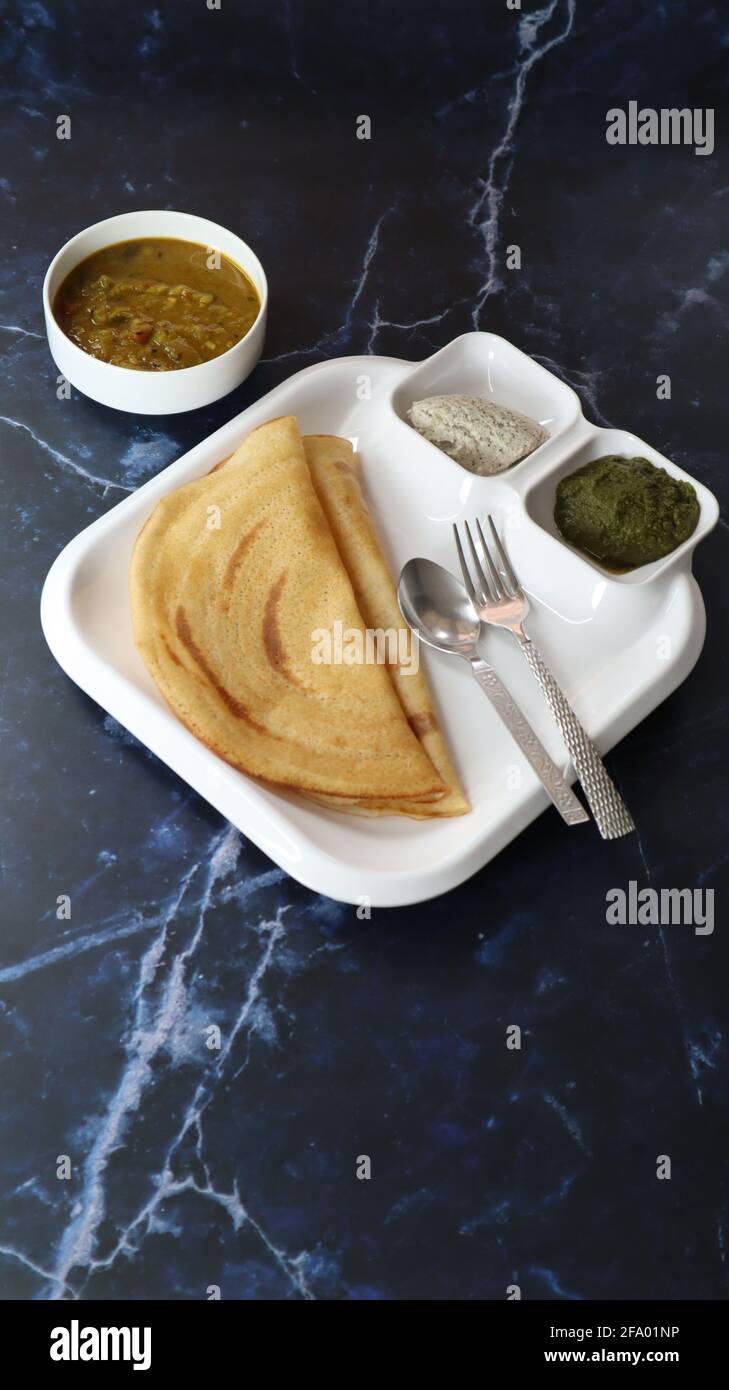 Dosa (Thin Pancake oder Crepe) ist eine südindische Mahlzeit, die mit sambhar und Kokosnuss-Chutney (Sauce) serviert wird, isoliert in einem anderen Hintergrund, einem anderen Stil Stockfoto
