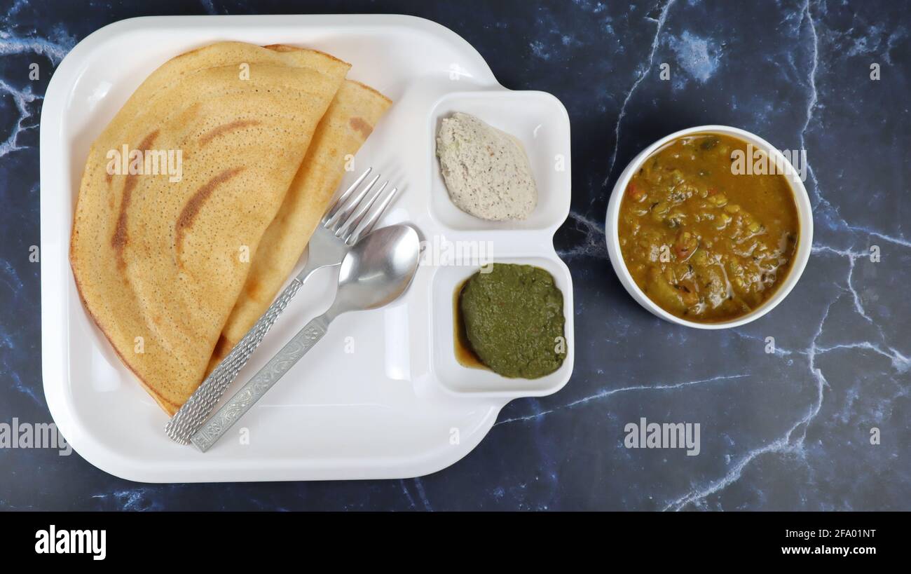 Dosa (Thin Pancake oder Crepe) ist eine südindische Mahlzeit, die mit sambhar und Kokosnuss-Chutney (Sauce) serviert wird, isoliert in einem anderen Hintergrund, einem anderen Stil Stockfoto