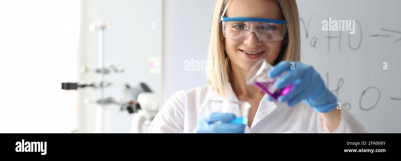 Frau Wissenschaftlerin in Sicherheitsgläsern Gießen chemische Lösung aus Kolben Im Labor Stockfoto