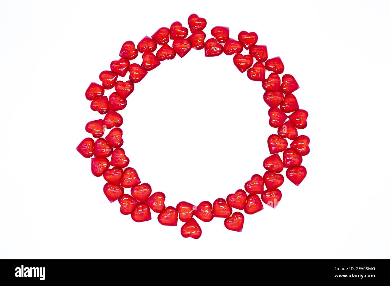 Leuchtend rote Herzen glänzen, Glas liegt in Form eines runden Rahmens auf weißem Hintergrund. Konzept der Liebe, Ehe, Hochzeit, Valentinstag, Leidenschaft Stockfoto