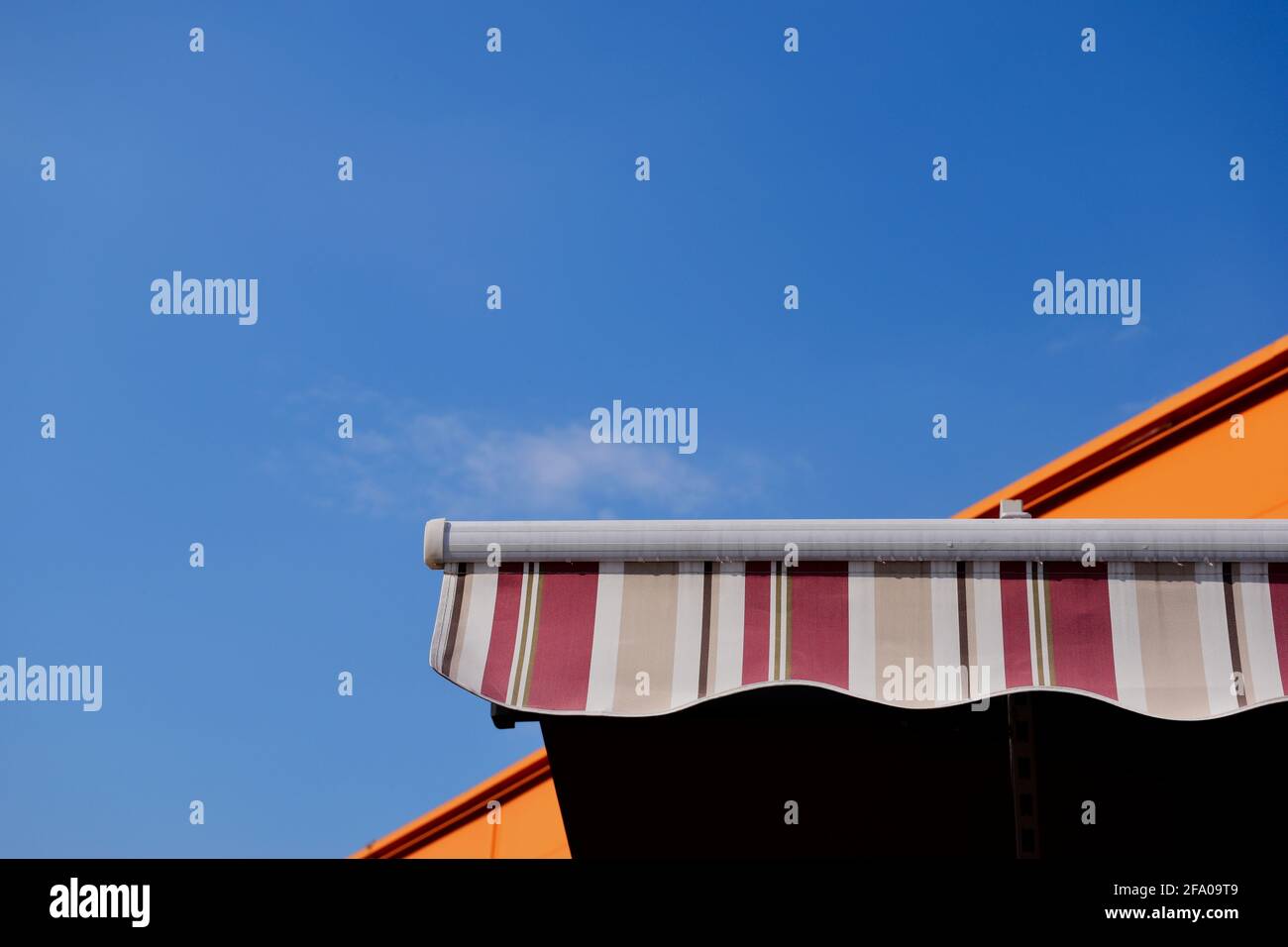 Einlauffähige Markise oder Zelt aus Segeltuch. Sonne- und UV-Schutz-Konzept. Blick in den hohen Winkel. Klarer blauer Himmel. Weiße Wolke. Heißer, klarer Sommertag. Regenfest. Stockfoto