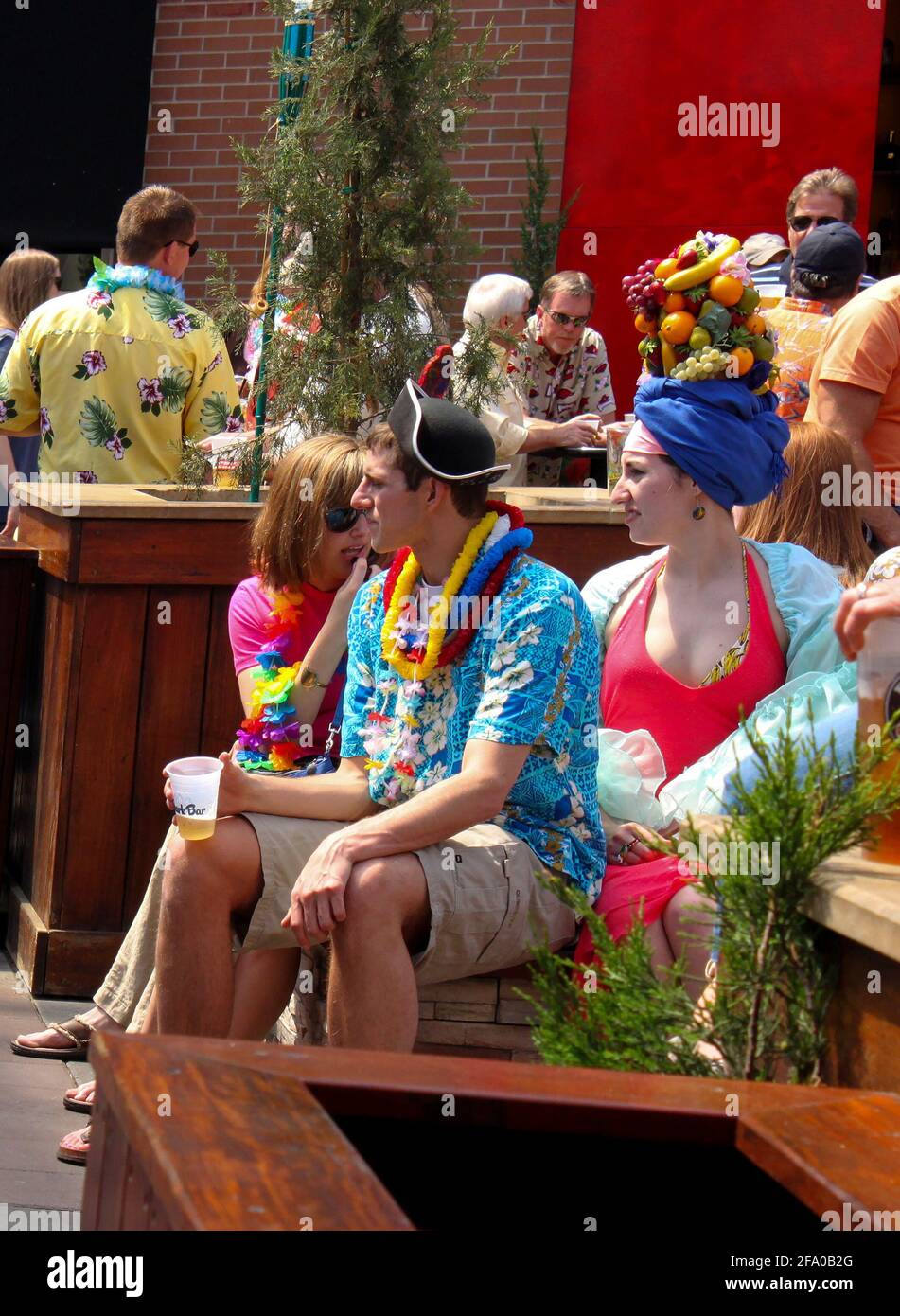 Familie in tropischer Kleidung... Frau mit Früchten auf dem Kopf Sitzen Sie mit anderen Partygängern im P&L District Kansas Stadt Mo USA Mai 5 2011 Stockfoto