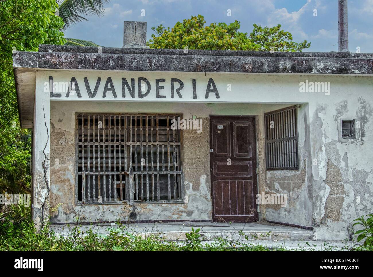 Mexikanischer Landromat oder Lavanderia in grungigem Altbau mit Stuck Von Betonblöcken und Holzstangen an Fenstern fallen - Unkraut wächst überall um ein Stockfoto