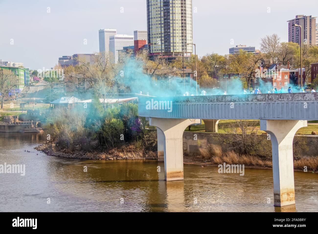 Die blaue Pulverstation auf einer Brücke über das Arkansas River auf einem Color holi Festival in Tulsa USA mit Menschen, die durch in der Ferne und die laufen Stockfoto