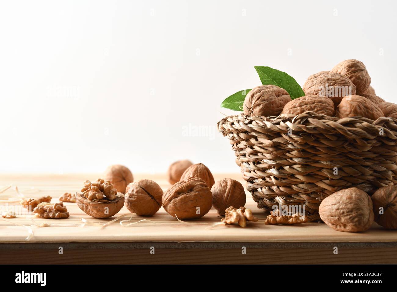 Korb voller Walnüsse auf einem Holztisch mit Spalt Walnüsse mit Samen in Sicht mit weißem isolierten Hintergrund Stockfoto
