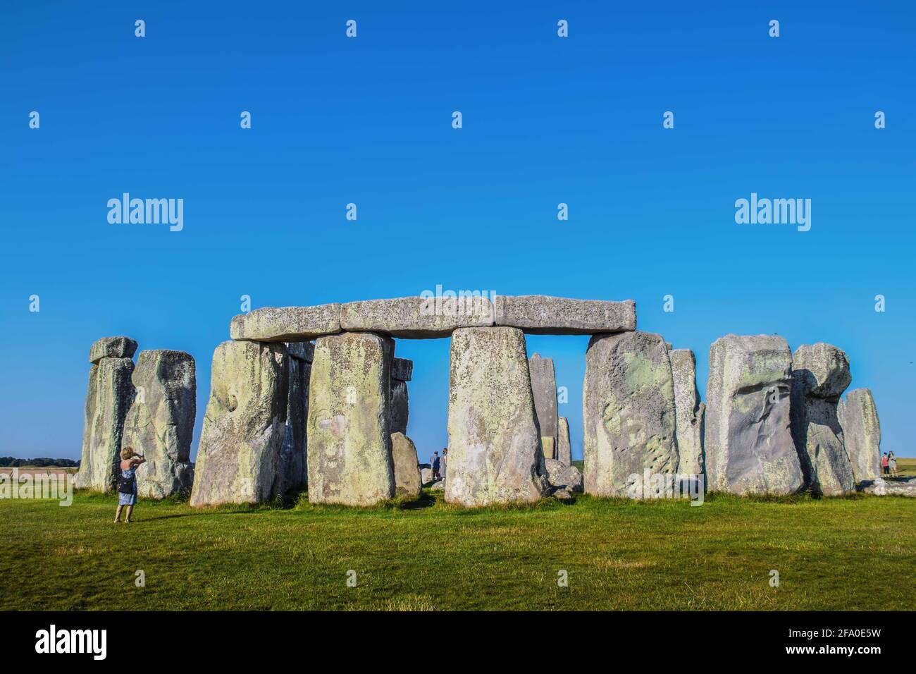 Altes Stonehenge auf der Salisbury Plain in Großbritannien mit einem Nur wenige Touristen drinnen und in der Umgebung gegen einen sehr blauen Himmel Stockfoto