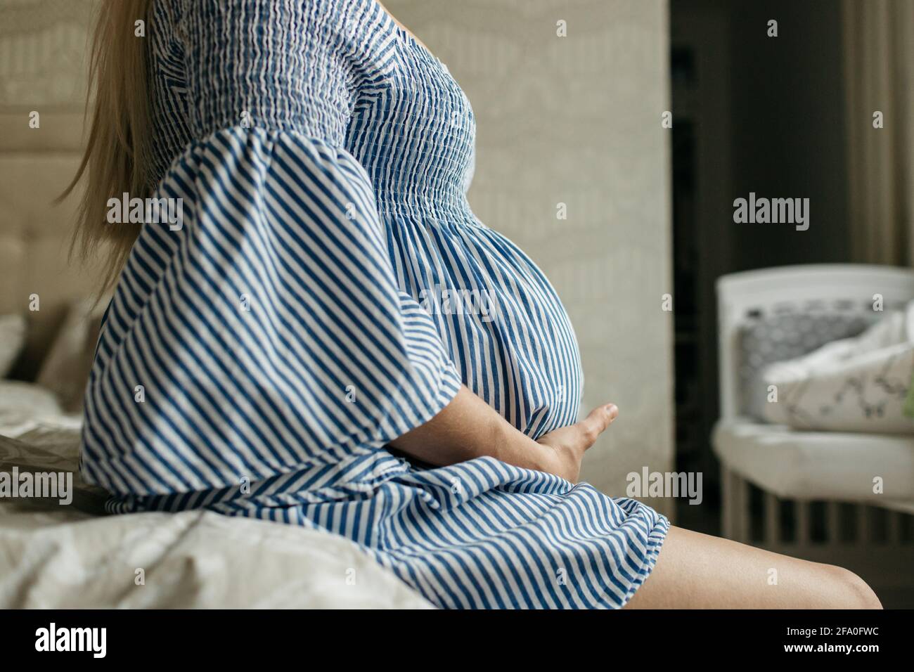 Eine Seitenansicht einer Schwangeren, die ihren Bauch berührt. Ein zugeschnittenes Bild einer Mutter, die ihren Schwangerschaftsbump hält. Stockfoto