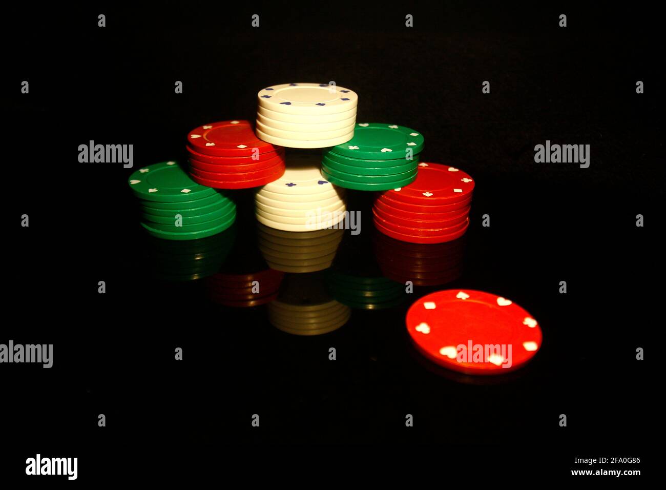 Stapel von Pokerchips mit einem roten Chip vorne Und Reflexionen isoliert auf Schwarz Stockfoto