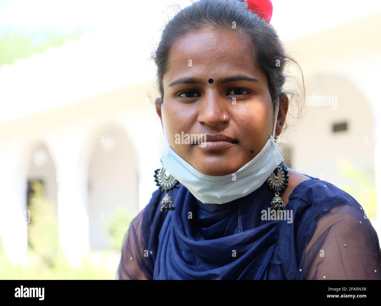 Flacher Fokus einer indischen Frau mit einer Gesichtsmaske Unter ihrem Kinn draußen Stockfoto