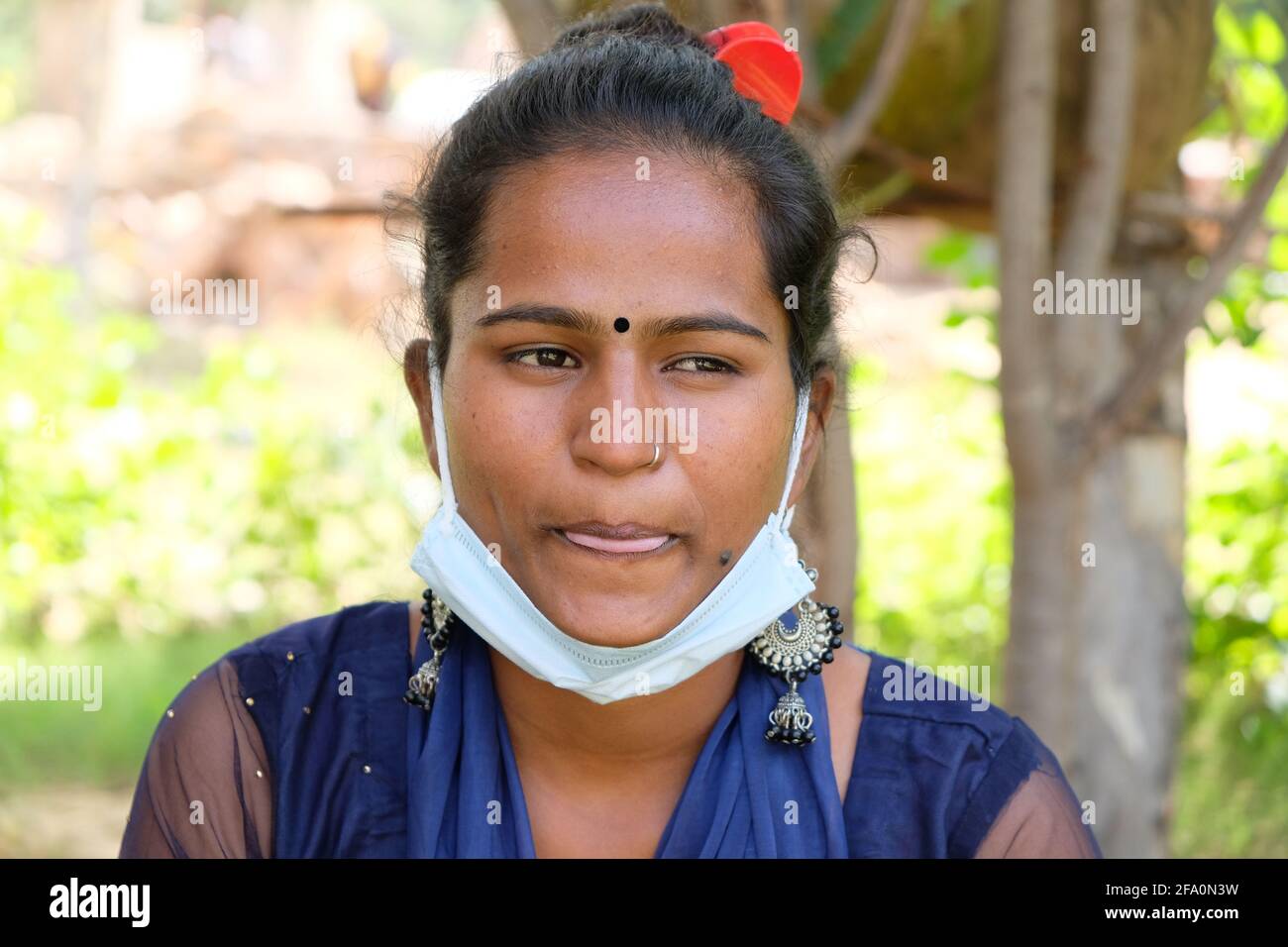 Flacher Fokus einer indischen Frau mit einer Gesichtsmaske Unter ihrem Kinn in einem Park Stockfoto
