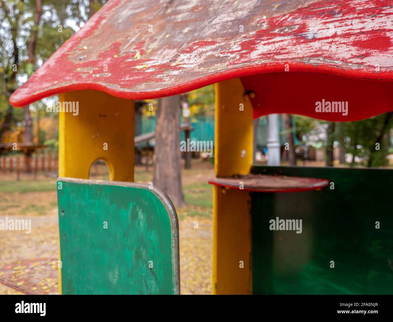 Verschwommenes Bild eines alten bunten Holzspielhauses auf dem Kinderspielplatz in einem Park. Nahaufnahme eines öffentlichen wendy's Hauses. Seilpark im Hintergrund. Stockfoto