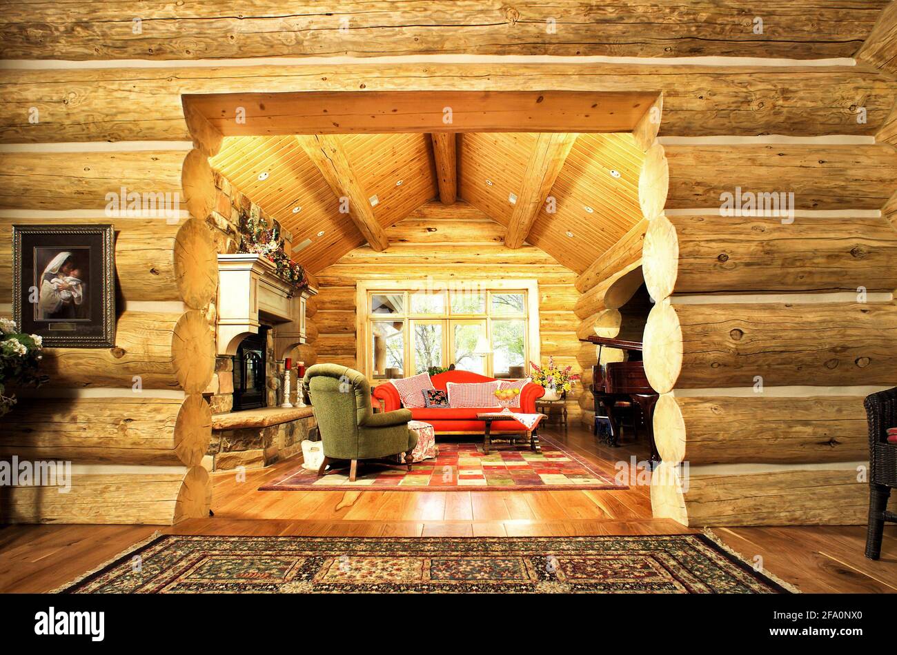 Ein luxuriöses Wohnzimmer, mit Kamin, Klavier und komfortablen Möbeln, in einer modernen Blockhütte in den Bergen. Stockfoto